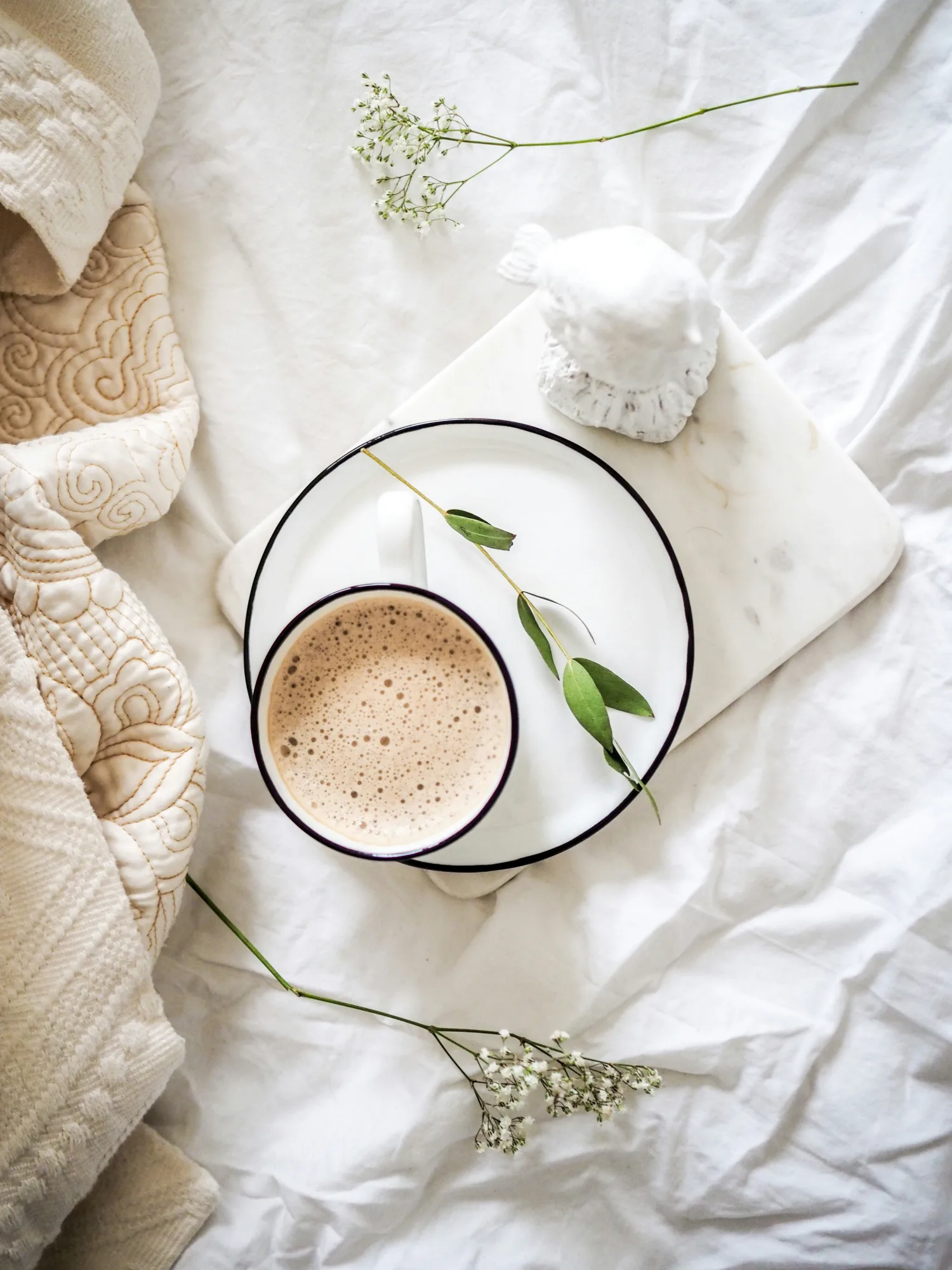 Tasse de café latte sur un plateau en marbre, décorée de feuilles d'eucalyptus